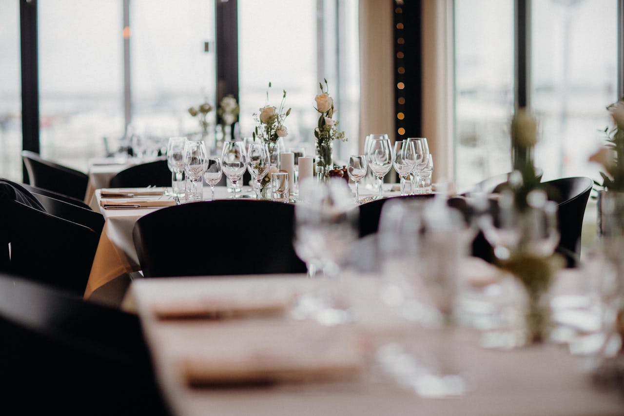 Elegantly set restaurant tables with wine glasses and floral centerpieces.